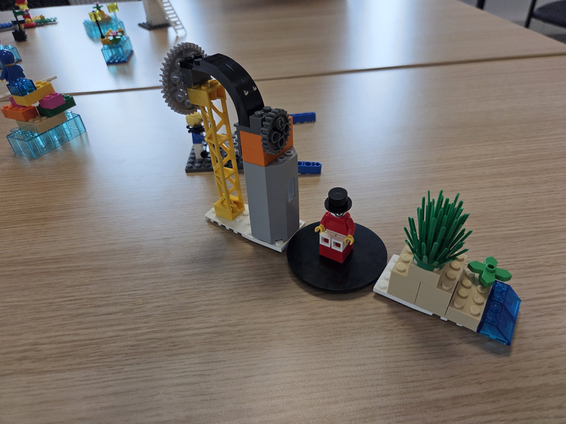 Drei LEGO-Modelle nebeneinander auf einem Tisch, im Hintergrund die Modelle der anderen Teilnehmenden